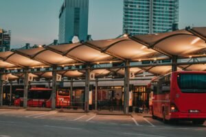 Illuminated bus station with parked buses in an urban setting at dusk.