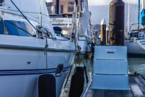 Detailed view of yachts moored at a marina with nautical equipment and serene water reflections.